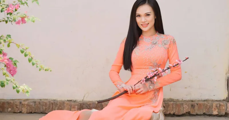 Cao Thuỳ Linh mượt m&agrave; với t&agrave; &aacute;o d&agrave;i hồng cam kết hợp b&ecirc;n b&ocirc;ng hoa anh đ&agrave;o.