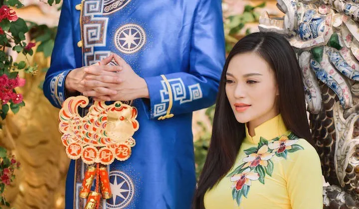 Ca sĩ Nhật Tinh Anh cũng chọn một chiếc &aacute;o d&agrave;i xanh cổ truyền thống Việt Nam l&agrave;m cho mạnh mẽ v&agrave; nam t&iacute;nh kết hợp với Cao Th&ugrave;y Linh b&ecirc;n cạnh chiếc &aacute;o d&agrave;i m&agrave;u v&agrave;ng thướt tha.